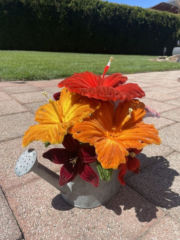 Orange Blüten aus Chenilledraht in einer Metallkanne